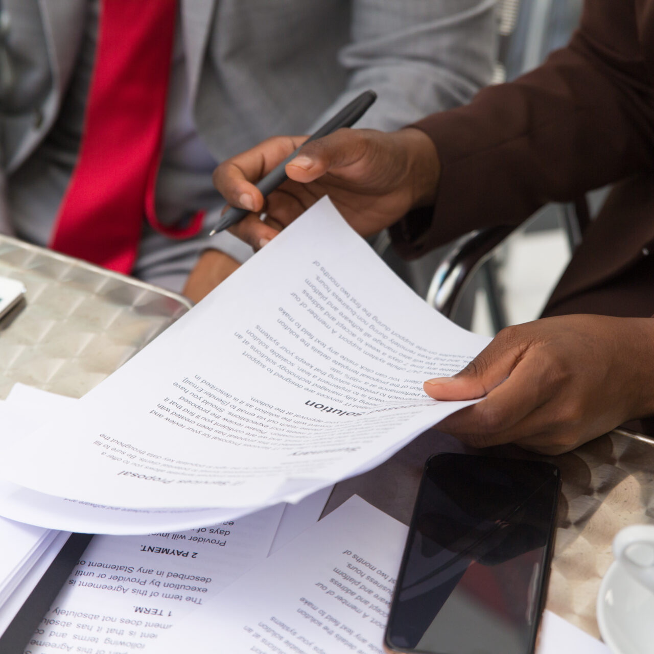 Businessman consulting legal expert in coffee shop. Closeup of business man and woman sitting in cafe and reading documents. Paperwork concept